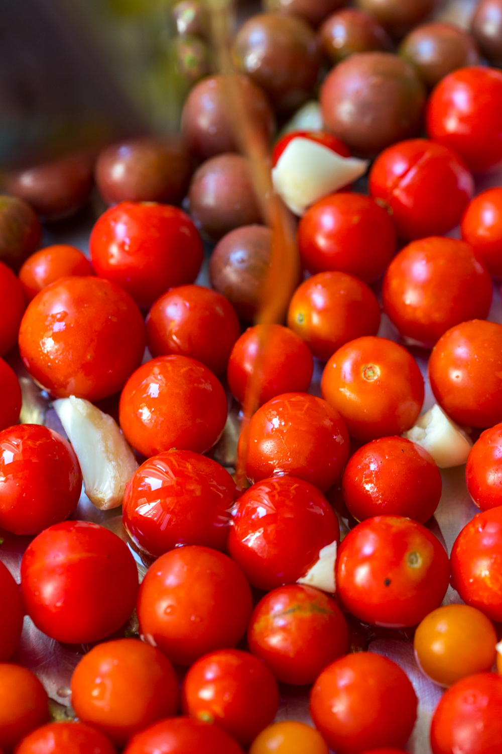 Olive oil drizzles on cherry tomatoes and garlic