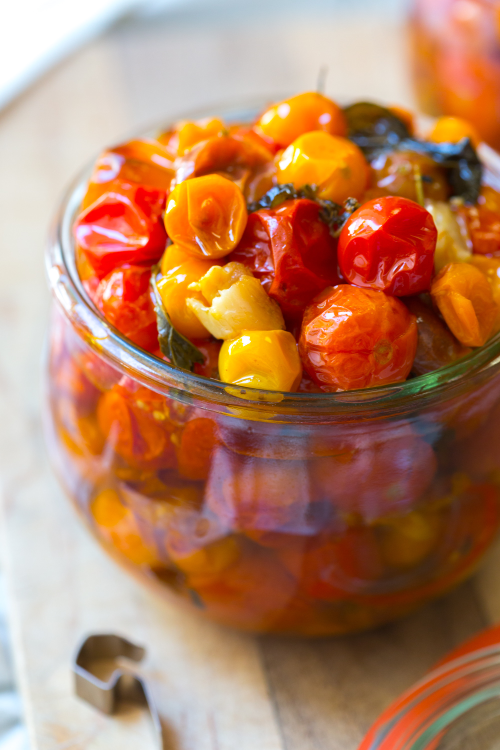 a close up of a jar of Cherry Tomato Confit, multi-colored tomatoes glistening in the light