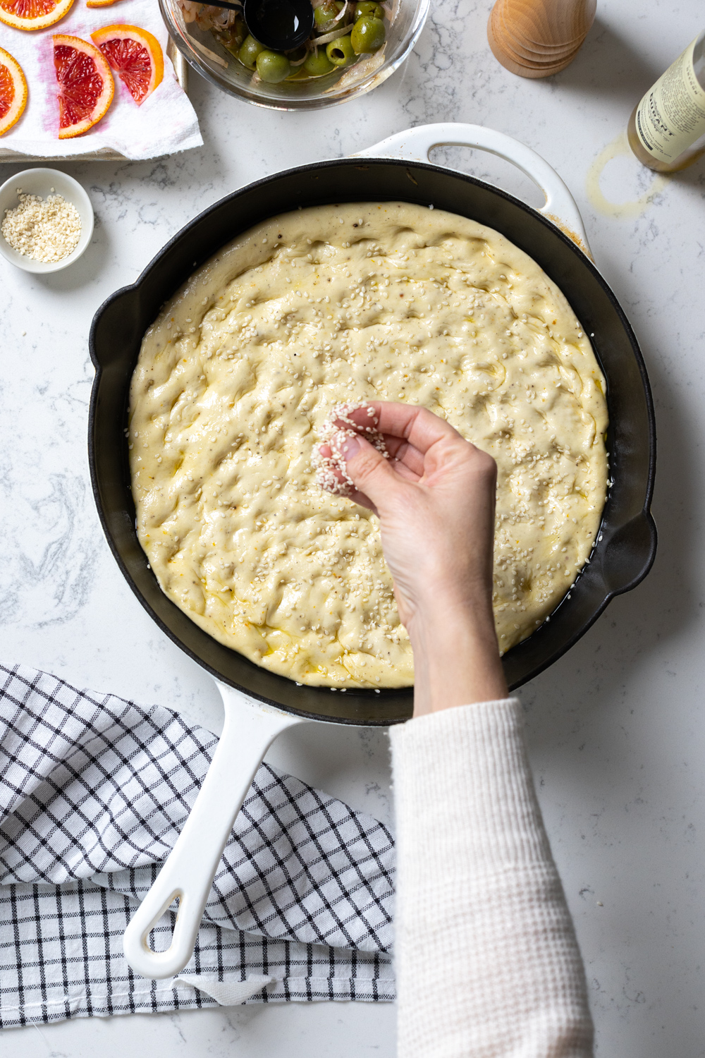 adding sesame seeds to focaccia dough