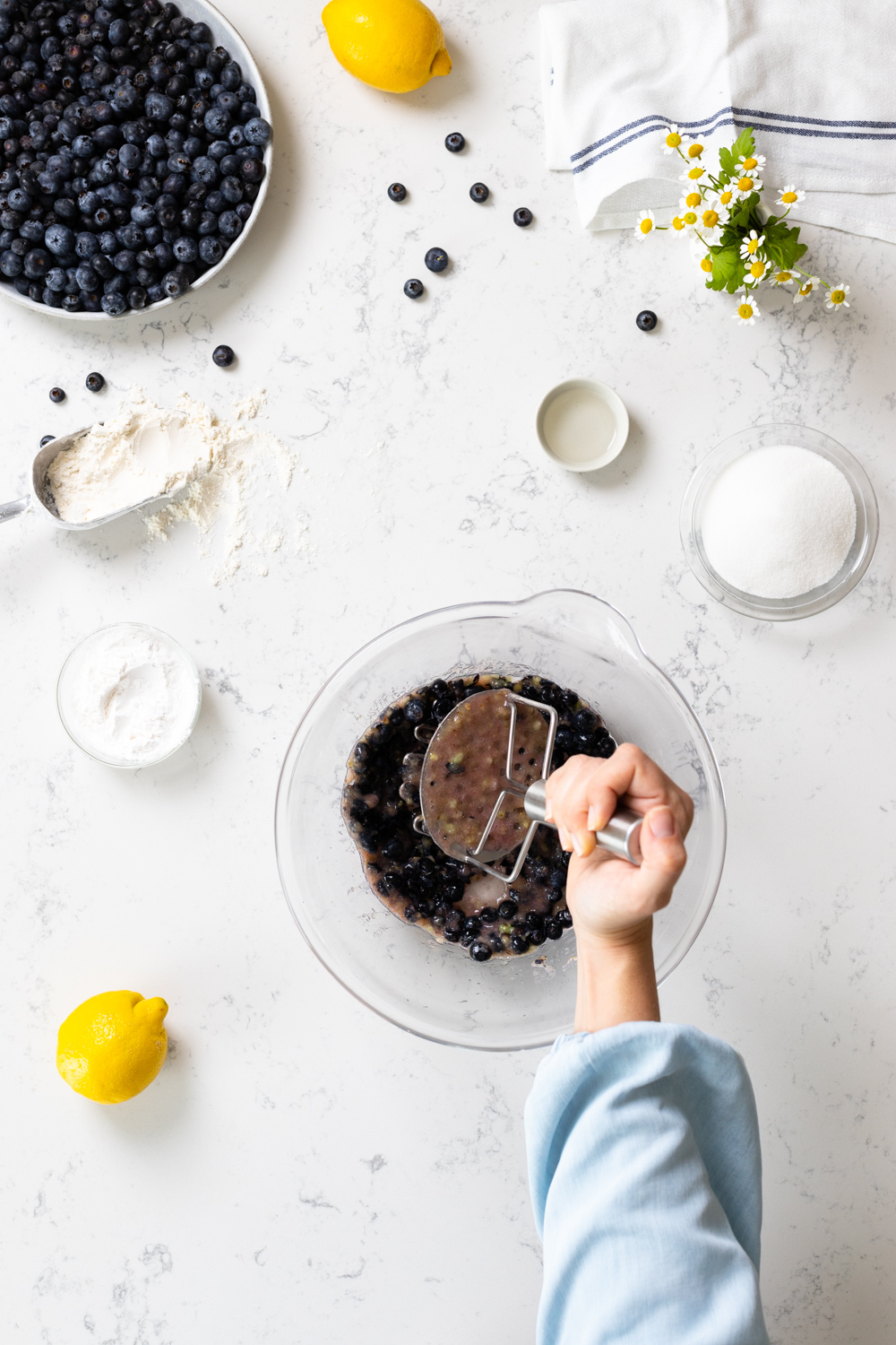 mashing blueberries with a potato masher