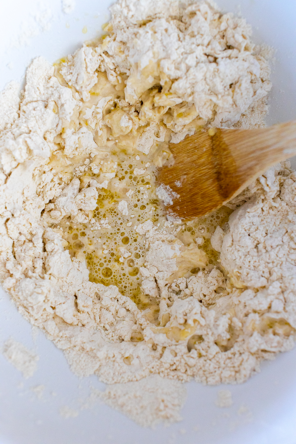 mixing pizza dough with wooden spoon