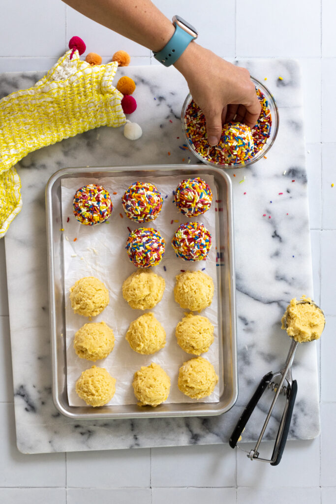Rolling lemon cookies in rainbow sprinkles