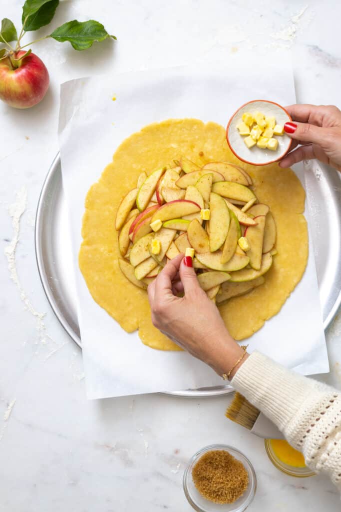 Dotting apple galette with butter