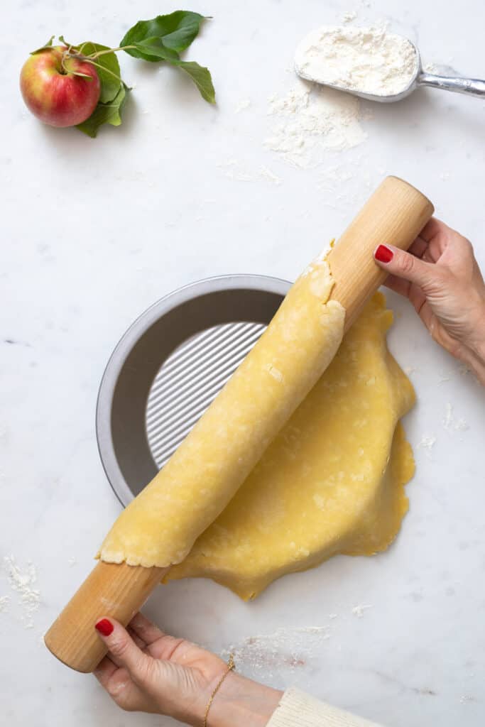 unrolling pie dough to pie dish