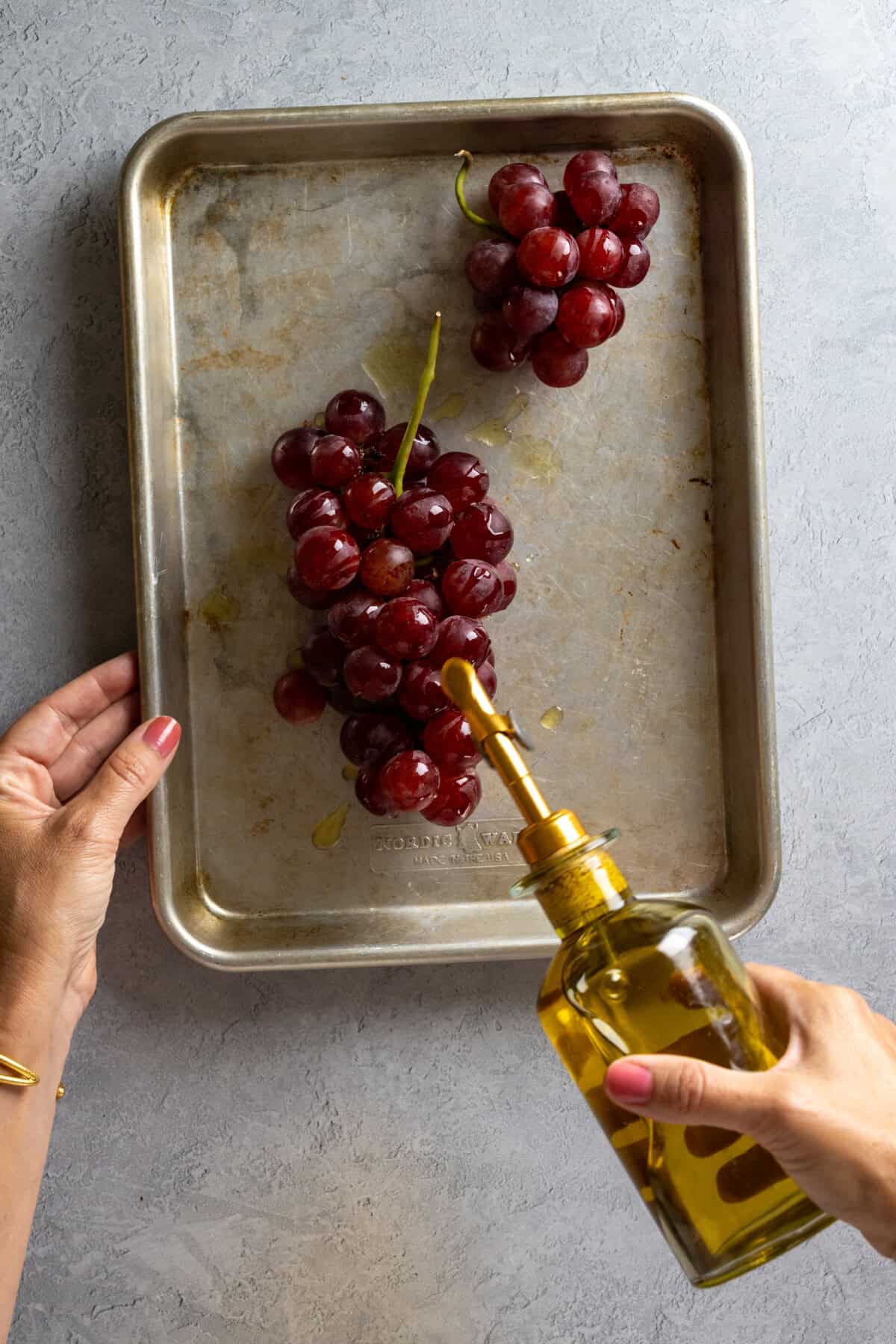 drizzling olive oil on grapes to be roasted
